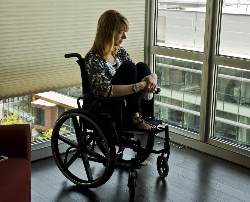 Woman in wheelchair looking plaintively out window